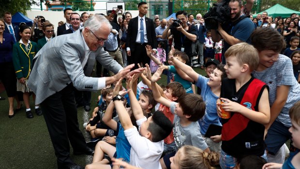 The Prime Minister gives high-fives to children at the school. 