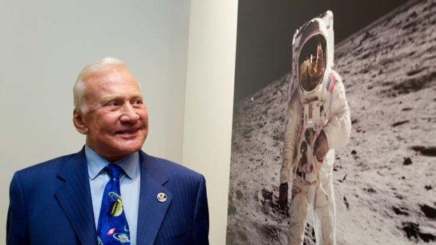Former astronaut Buzz Aldrin looks at a photo of himself on the moon.