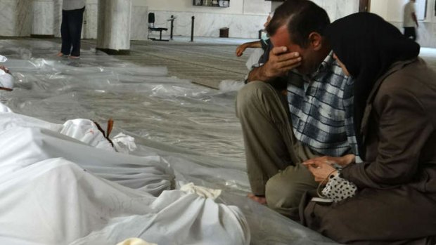 A couple mourn in front of bodies wrapped in shrouds following what Syrian rebels claim was a toxic gas attack by pro-government forces.