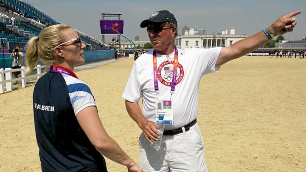 Britain's eventing individual champion and granddaughter of Queen Elizabeth II, Zara Phillips (left), chats with her father and coach of the US eventing team, Mark Phillips, at the equestrian arena in London.