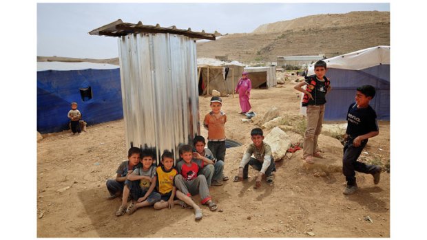 Syrian children in the Arsal refugee camp sit next to a new toilet built to accommodate the influx of people fleeing the war.