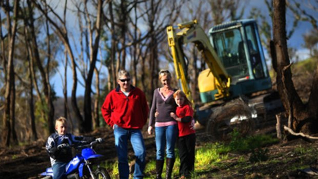 Kerry and Bruce Williams with son Josh and daughter Ella and the family excavator which was seen as a cost effective way of clearing their Steels Creek property after the devastation of the Black Saturday fires.
