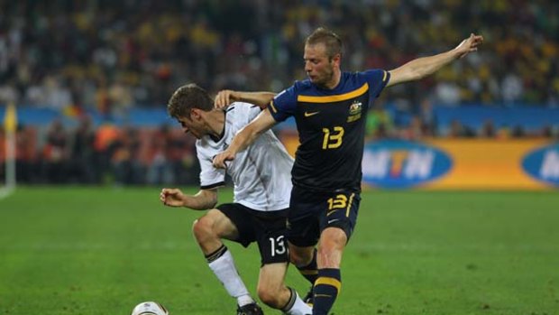 Be a man ... midfielder Vince Grella attempts to tackle Germany's Thomas Muller in Durban.