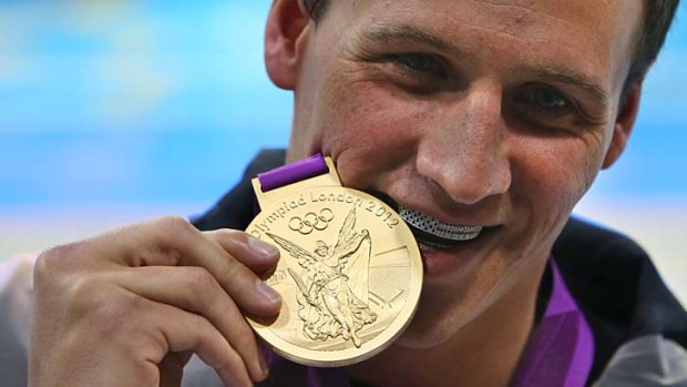 Golden boy: Ryan Lochte wears a US$25,000 American flag grill as he bites into his gold medal at the 2012 London Olympics.