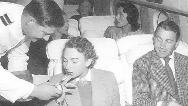 How it once was: A Qantas steward helps a passenger light up.