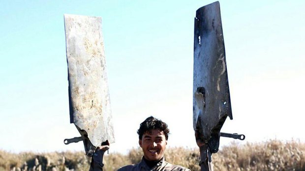 An IS fighter holds pieces of the Jordanian warplane near Raqqa, Syria.