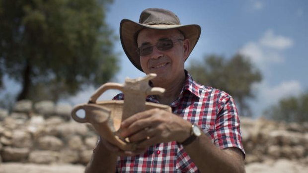 Professor Yossi Garfinkel holds an article from his archaeological excavation next to the remains of what is thought to be King David's palace.
