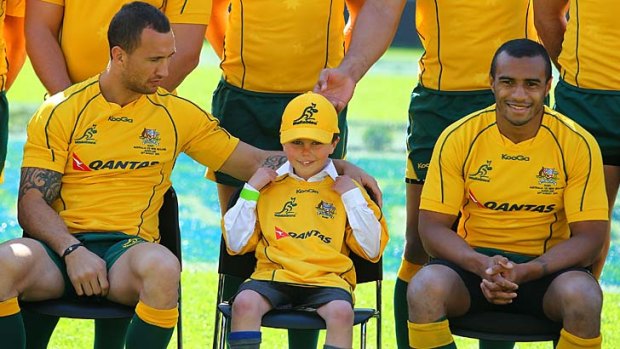 Quade Cooper pats a young fan as he and Wallabies captain Will Genia wait for a team photo to be taken at Eden Park yesterday.