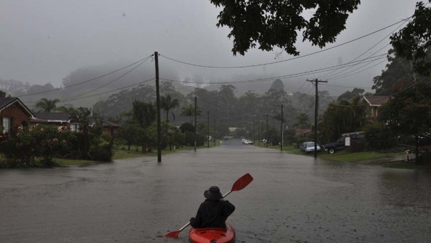 A resident in a kayak negotiates flooded streets in Coffs Harbour as torrential rain hammers the region.
