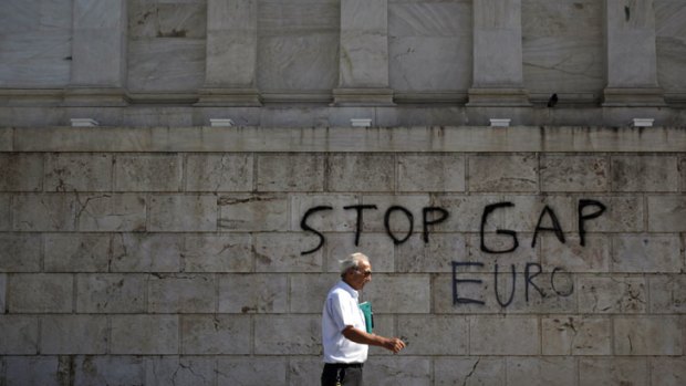 A pedestrian passes anti-government graffiti which reads "Stop GAP Euro" referring to George Papandreou, Greece's prime minster.