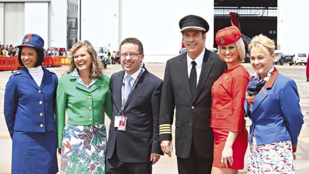 Frequent flyers... Alan Joyce and John Travolta with flight attendants dressed in uniforms from different eras.