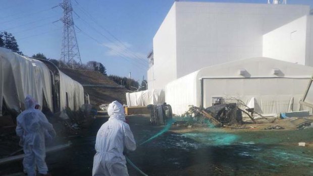 Tokyo Electric Power Co. workers spray adhesive synthetic resin over the ground at the Fukushima Dai-ichi nuclear power plant.