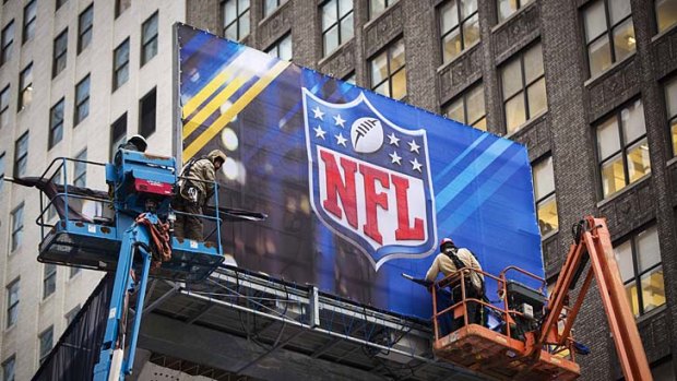 Workers hang signage on a booth on Broadway as preparations continue for Super Bowl XLVIII.