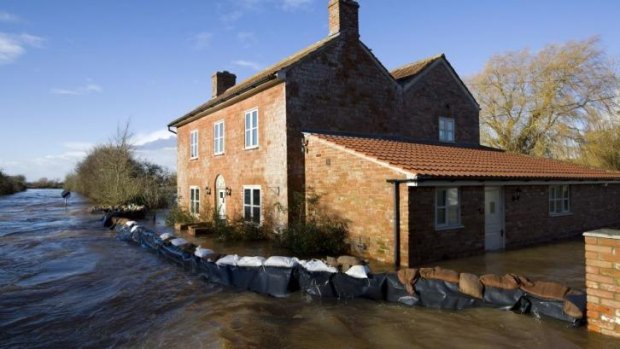 Flood waters engulf a house with a wall of sandbags around it in Burrowbridge.