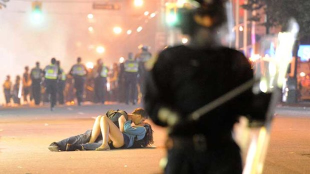 Australian Scott Jones plants a kiss on his Canadian girlfriend, Alex Thomas, during a riot in Vancouver.