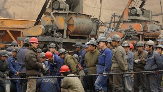 Workers wait outside the entrance to the Wangjialing coal mine as rescuers try to find more than 150 trapped miners.