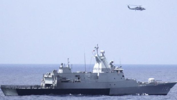 The Royal Malaysian Navy corvette KD Terengganu and a US helicopter conduct a coordinated air and sea search for a missing Malaysian Airlines jet in the Gulf of Thailand. 