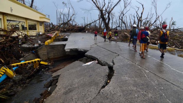 Survivors walk over a collapsed bridge in an area devastated by Typhoon Haiyan.