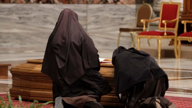 Two nuns knees over the casket of late Cardinal Bernard Law.