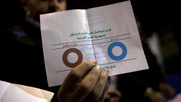 An Egyptian election worker shows an invalid ballot while counting votes.