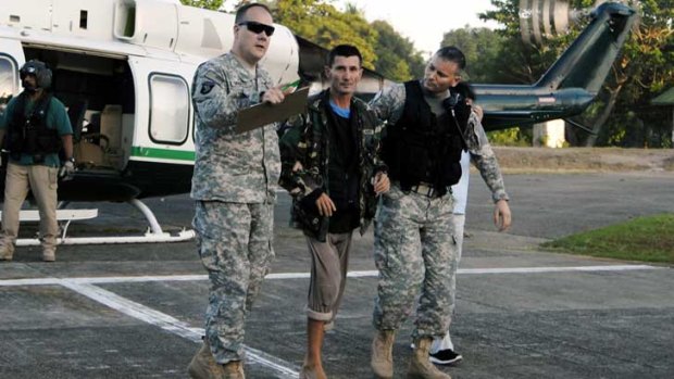 Warren Rodwell is escorted from a helicopter by US soldiers at a military base in Zamboanga City.