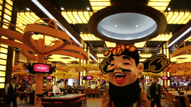 A man dressed as a Chinese God of Fortune walks inside the newly opened Resorts World Sentosa casino.