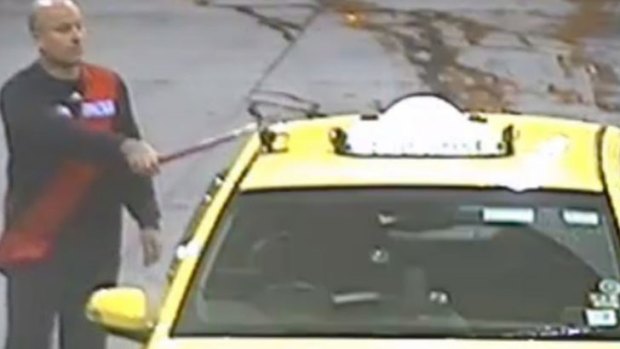 The offender captured on CCTV hittin the taxi with a window-washing squeegee.