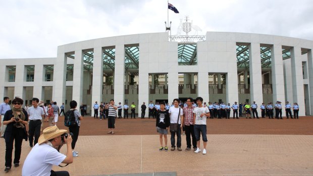 Tourists take photos of each other on the forecourt of Parliament House Canberra. 