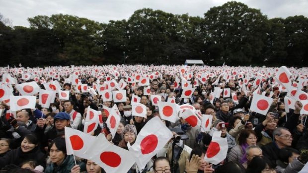 Well-wishers wave Japanese flags to celebrate Emperor Akihito's 80th birthday.