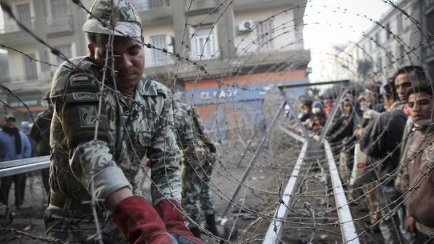 An Egyptian soldier helps to put a barbed wire barricade in place, near Tahrir square in Cairo, Egypt.