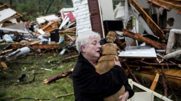 Constance Lambert embraces her dog after finding it alive on returning to her destroyed home in Tupelo.