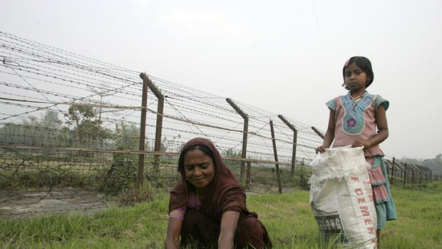 A woman and her daughter pick grass on the Indian side of the border fence with Bangladesh.