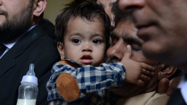 Nine month old Pakistan toddler Mohammad Musa is held by his grandfather Muhammad Yasin for the court heading in Lahore on April 12. The court threw out charges of attempted murder against the baby.