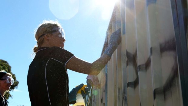 At the wall face ... volunteer Skye Norford cleans off graffiti in Lalor Park.