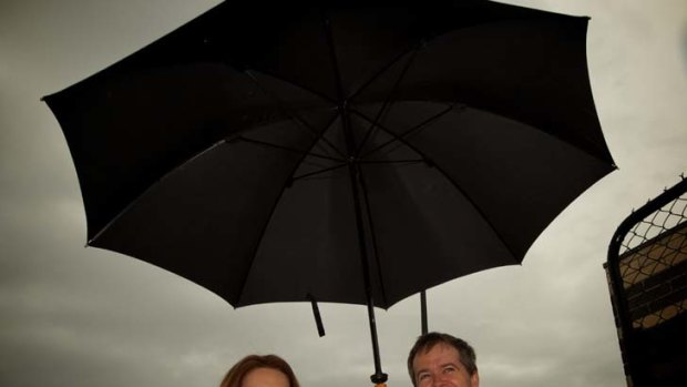 Taking cover &#8230; the Prime Minister, Julia Gillard, with the Assistant Treasurer, Bill Shorten, in Melbourne yesterday to promote the government's carbon tax.