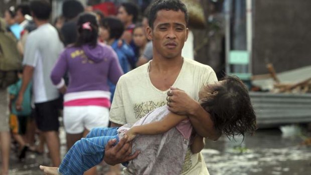 A father carries the lifeless body of his daughter on the way to the morgue after super typhoon Haiyan hit Tacloban City in Leyte province, central Philippines.