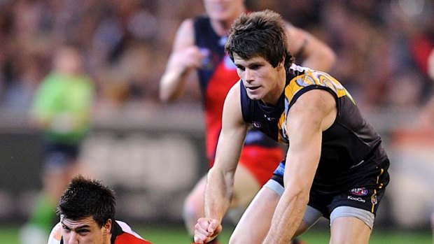 Short shrift: Bomber Angus Monfries dishes off a handball as Tiger Trent Cotchin closes in.