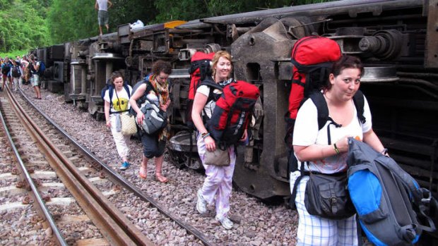 Lucky escape: Passengers carry their belongings from the derailed train.