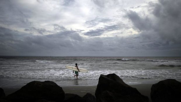 Kevin Taylor of Savannah, Georgia, heads out to surf the waves on the north beach of Tybee Island as Hurricane Arthur makes its way up the East Coast.