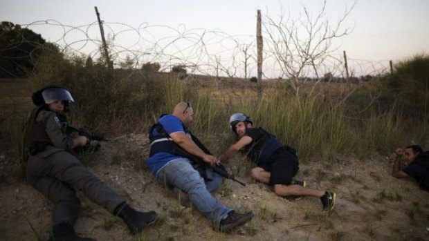 Israeli police and security personnel take cover during an infiltration by Palestinian gunmen near Kibbutz Zikim.