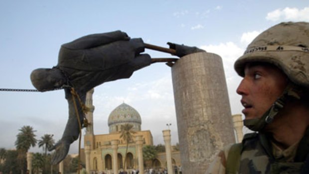 A US soldier watches as a statue of Saddam Hussein falls in Baghdad on April 9, 2003.