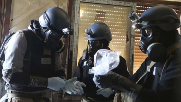 A UN chemical weapons expert, wearing a gas mask, holds a plastic bag containing samples from one of the sites of an alleged chemical weapons attack in the Ain Tarma neighbourhood of Damascus.