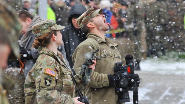 A US Army soldier plays with falling snow during the official welcoming ceremony of the US troops in Zagan, Poland this month. 