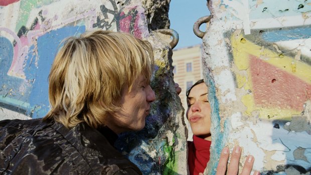 No stopping love: A couple blow kisses to each other through the mural-covered remains of the Berlin Wall.