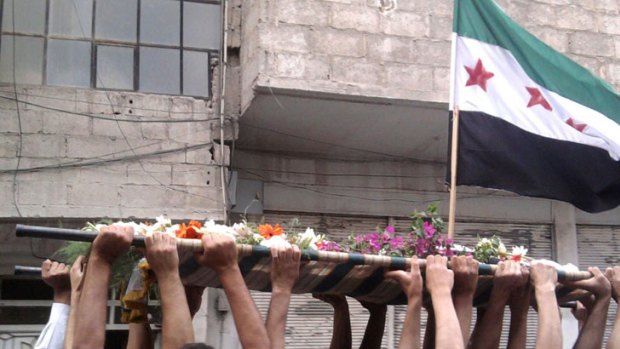 A handout image released by the Syrian opposition's Shaam News Network shows the the old Syrian flag adopted by the Free Syria Movement during the funeral procession of Ramez al-Sharif in Irbin.
