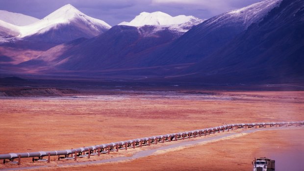 A truck travelling beside a major oil pipeline on a remote highway in Alaska.