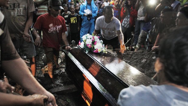 Relatives lower the coffin of Hayati Lutfiah Hamid at her burial in Surabaya.