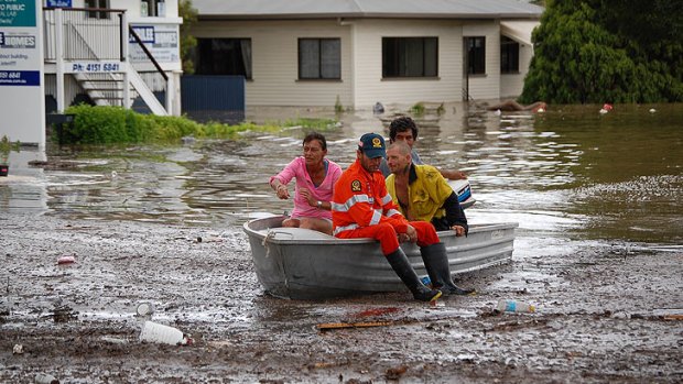 An SES worker helps ferry passengers from their water-logged homes in Bundaberg.