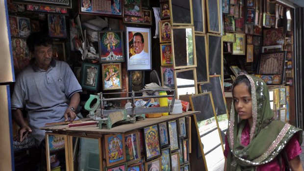 A Sri Lankan Muslim woman walks past a picture framing shop where a portrait of President Maithripala Sirisena is on display.