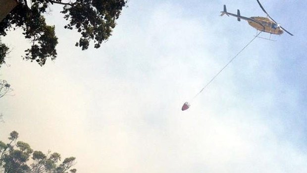 A helicopter water bombs a Bribie Island bushfire.